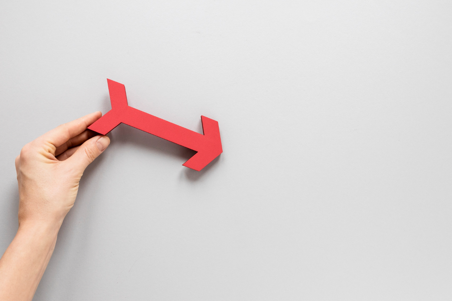 Flat lay hand holding red arrow