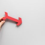 Flat lay hand holding red arrow